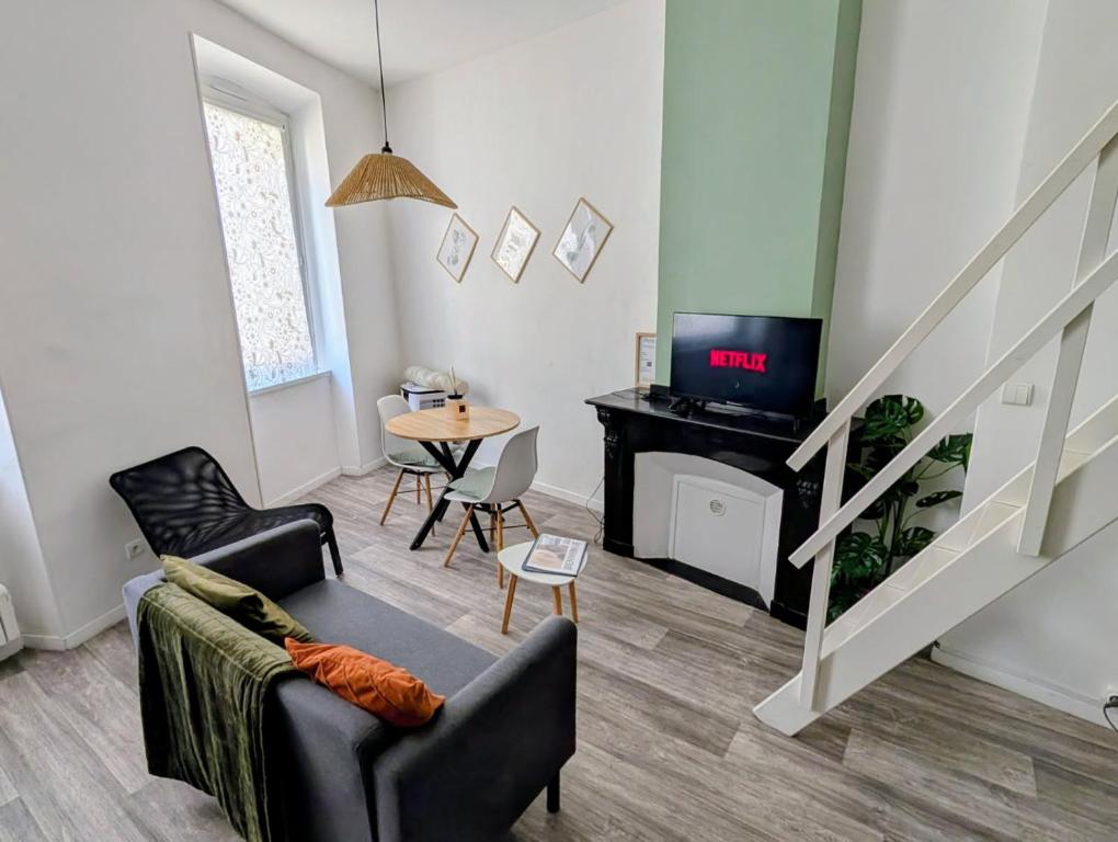 a living room with a couch and a tv and a table at Escapade cœur de ville Narbonne in Narbonne