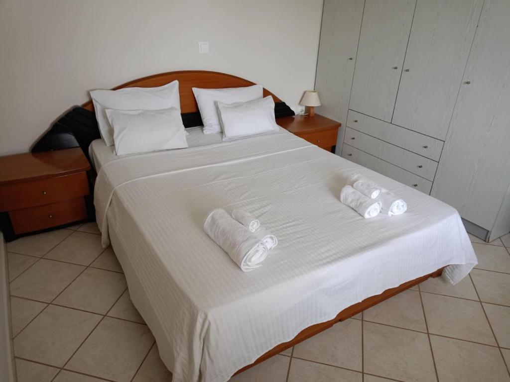 une chambre avec un grand lit avec des draps et des oreillers blancs dans l'établissement Anna Family Apartment, à Nikiti