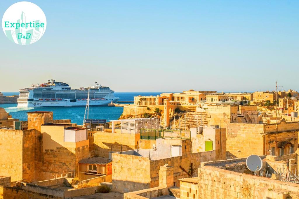 a cruise ship in the water with buildings at Kharmen A 1565s House with Seaviews in Birgu