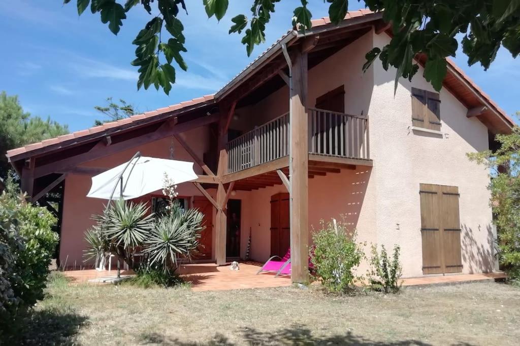 une maison avec un balcon et un parasol dans l'établissement La Casa d'Annick, à Moliets-et-Maa