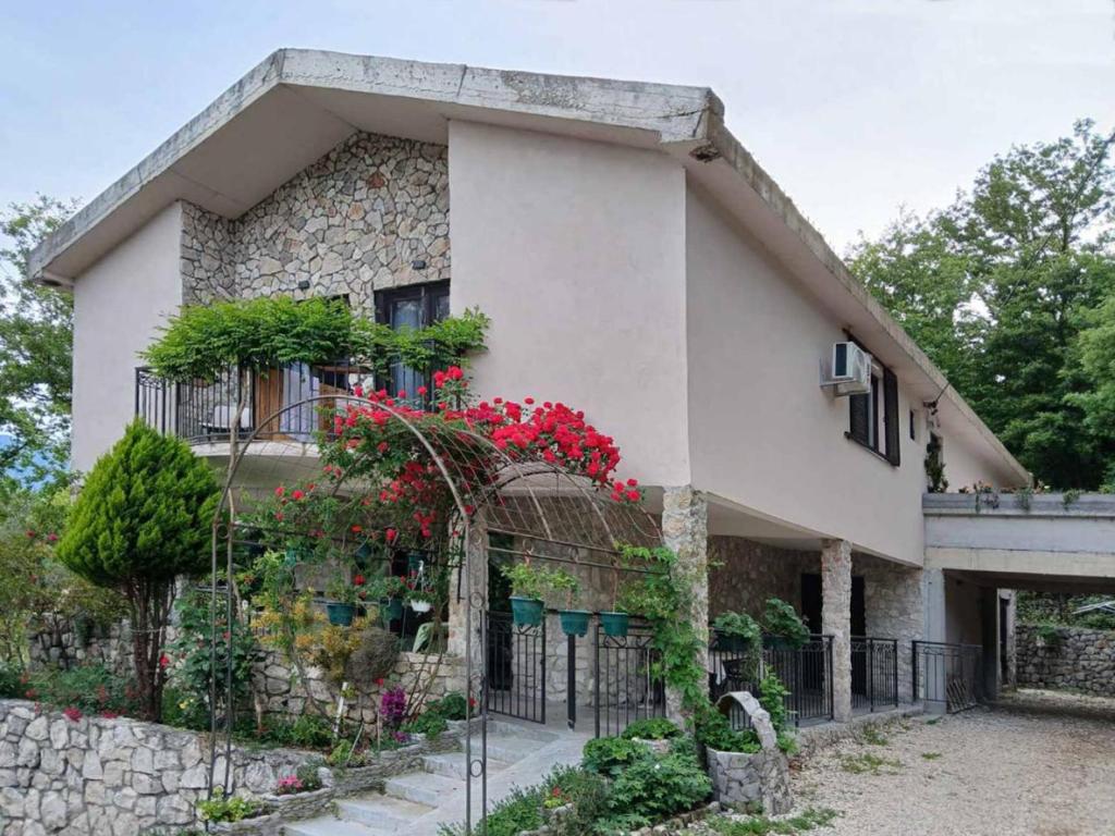 a house with red flowers on the side of it at Dado in Virpazar