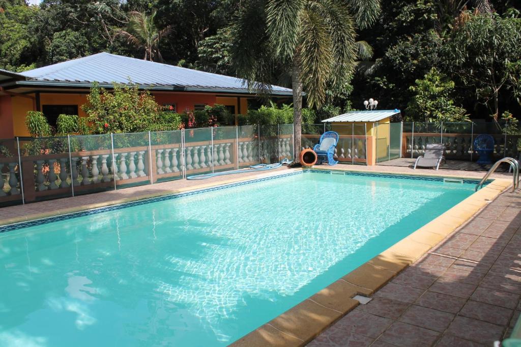 una gran piscina azul junto a una casa en Hotel L'ebene Verte en Matoury