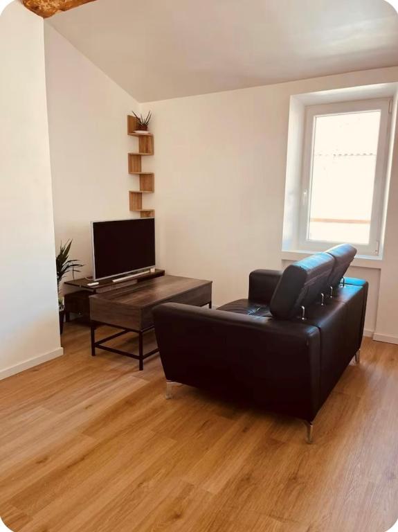 un salon avec un canapé noir et une table dans l'établissement La chrysalide, à La Crau