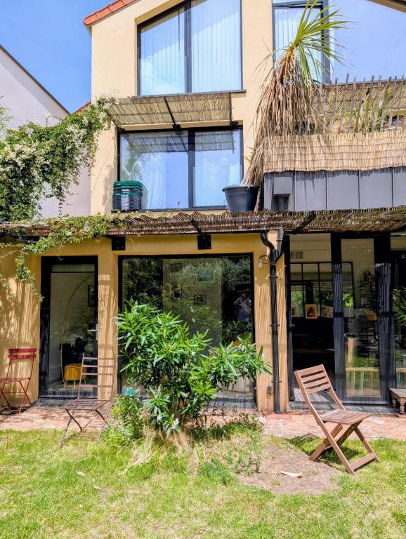 une maison avec un toit de paille et une chaise dans l'établissement Bright house 10m from Paris, à Sèvres