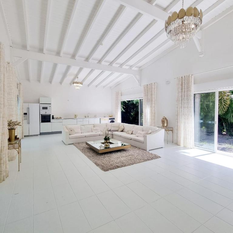 a large living room with white furniture and a chandelier at Sandy Bay Villa Opale in Le Moule