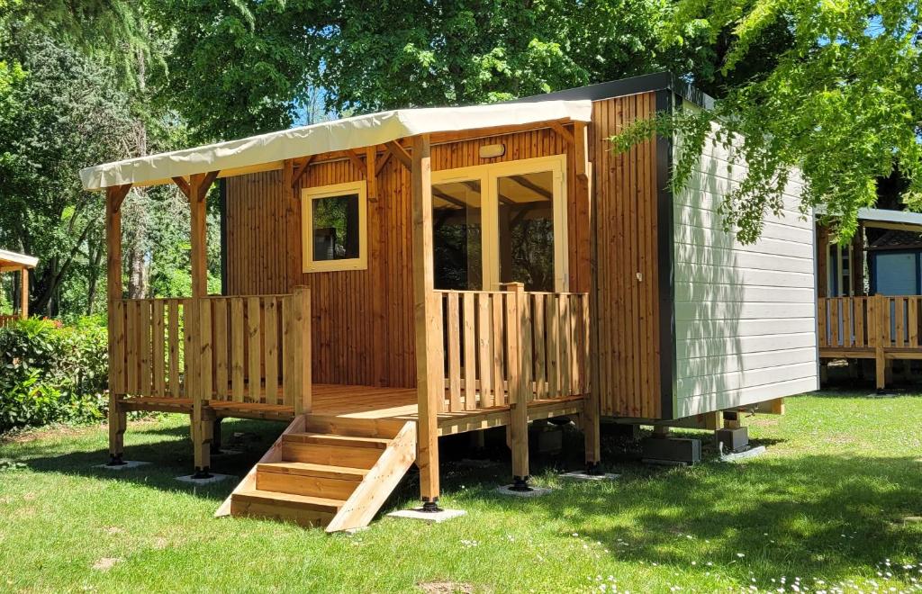 Cabaña de madera con porche y escaleras en el césped en Camping Portes d&#39;Ariege, en Pamiers