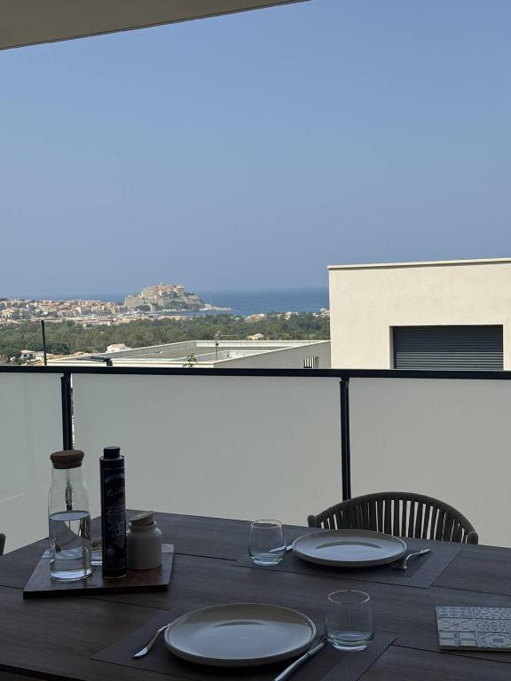 une table avec des assiettes et des verres sur un balcon dans l'établissement Appartement avec vue sur la mer et la citadelle, à Calvi