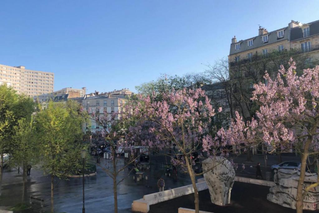 un groupe d'arbres à fleurs roses dans une ville dans l'établissement Cosy apartment in the 11th arrondissement, à Paris