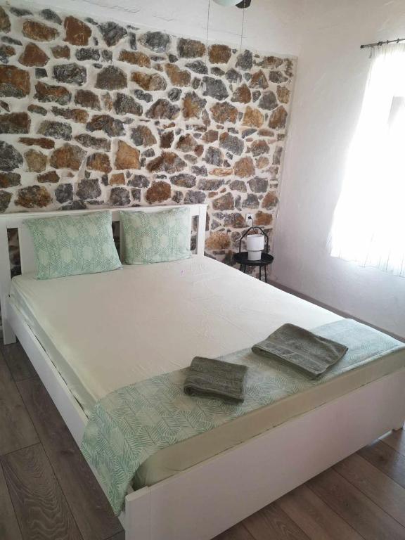a bed in a room with a stone wall at Mandal Cottage in Samothraki