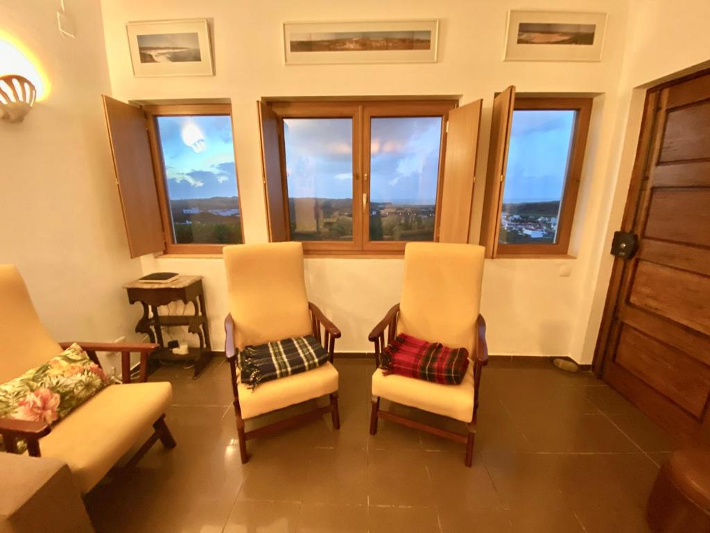 a living room with chairs and windows at Casa do Miradouro in Carrapateira