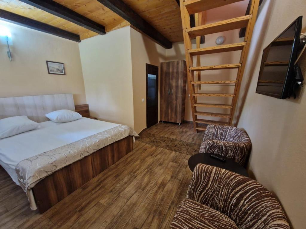 a bedroom with a bed and a ladder and two chairs at Vila Sura Razoare in Sighişoara