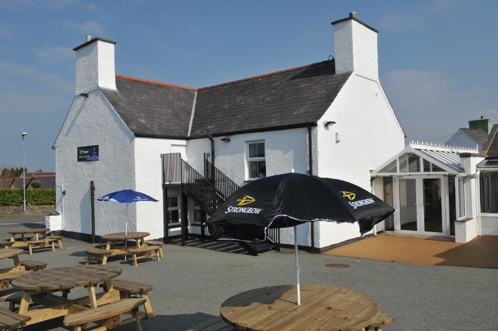 a building with tables and an umbrella in front of it at California Hotel in Brynteg