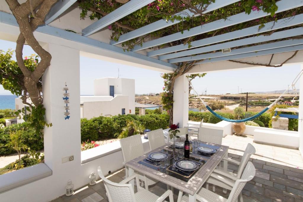 a table and chairs on a patio with a view of the ocean at Villa Maria, Golden Beach, Paros in Kampos Paros