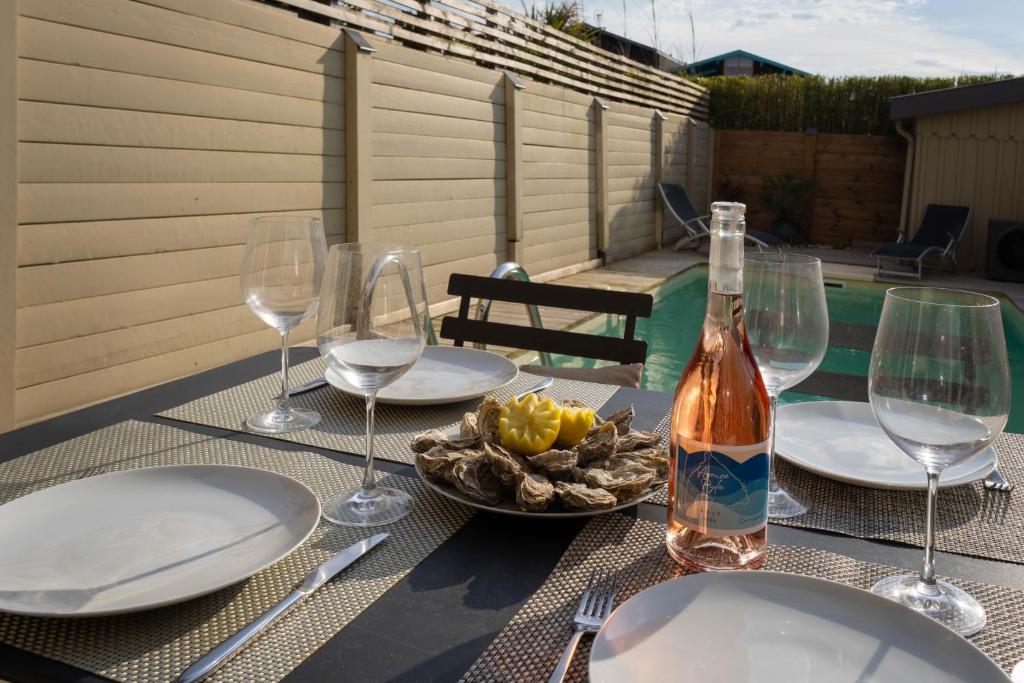 - une table avec une bouteille de vin et des verres à vin dans l'établissement Superbe maison lumineuse, au calme avec piscine, à La Teste-de-Buch