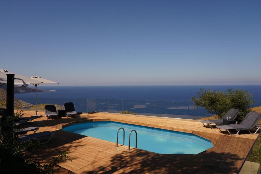 a swimming pool with chairs and a view of the ocean at House of Harmony Standaard studio Mira ADULTS ONLY in Achlada