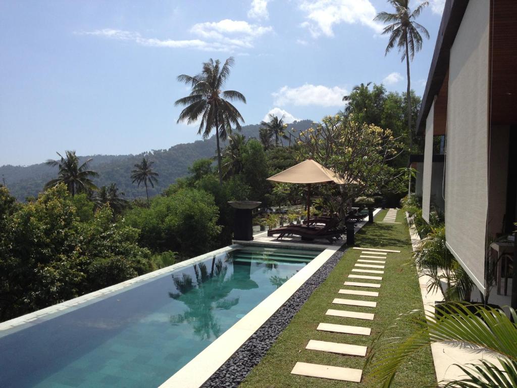 a swimming pool with a view of a house at The Puncak Lombok in Senggigi