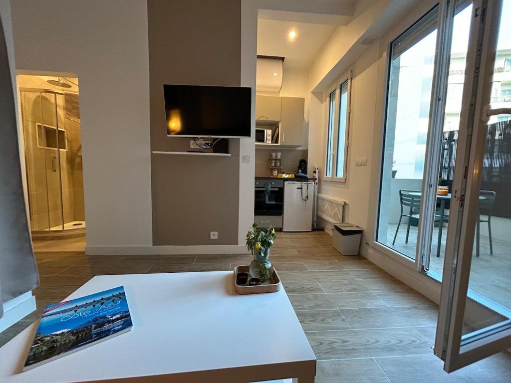 Il comprend un salon doté d'une table blanche et d'une télévision. dans l'établissement Central studio and sun terrace, à Nice