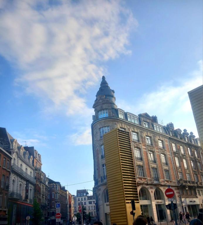un grand bâtiment avec une tour dans une rue de la ville dans l'établissement Framboise, à Lille