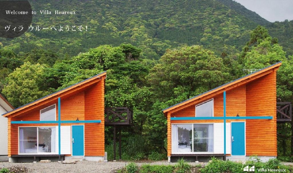 a house with orange and blue windows in front of a mountain at Villa Heureux in Yakushima