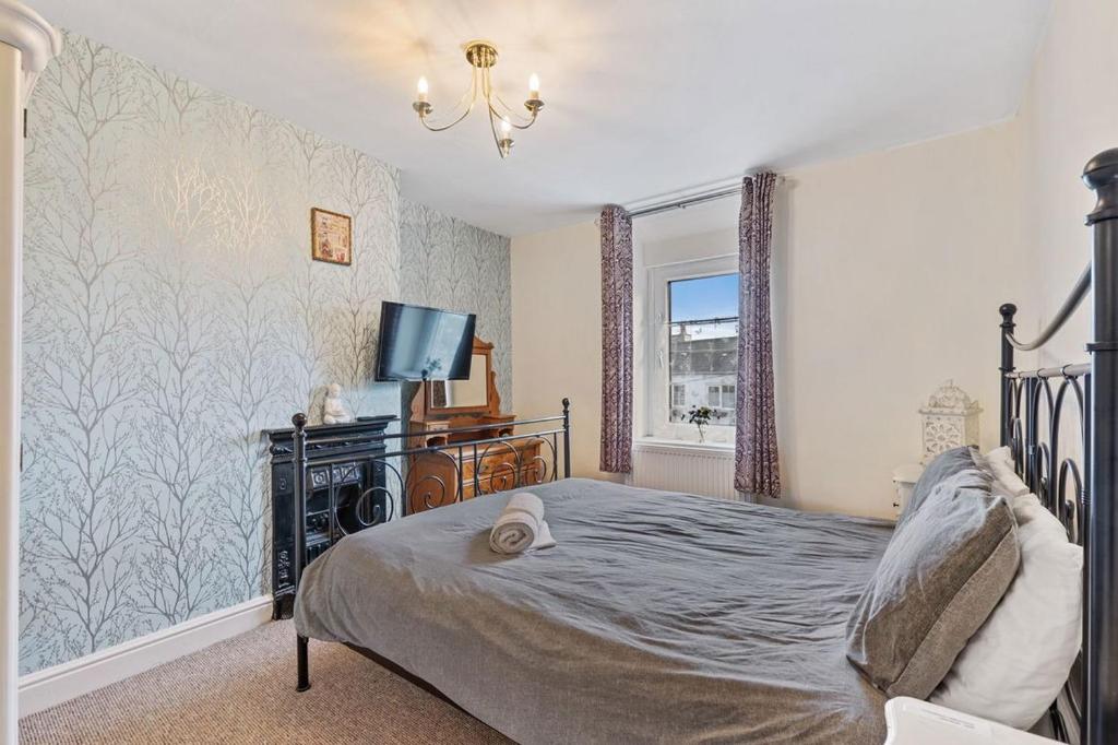 a bedroom with a bed and a tv and a window at 4 bedroom house near Burton Latimer, Wellingborough and Isham in Isham