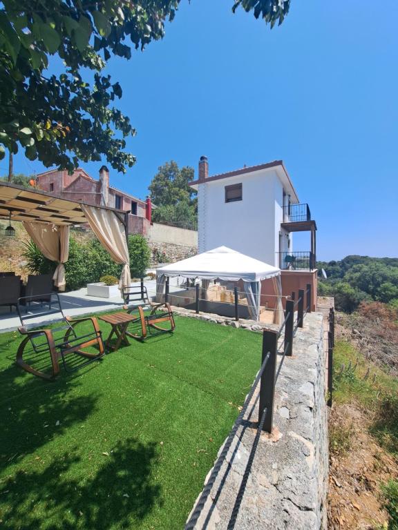 a backyard with a lawn with picnic tables and a building at Iordanis house- Traditional House in old Alonnisos in Alonnisos Old Town