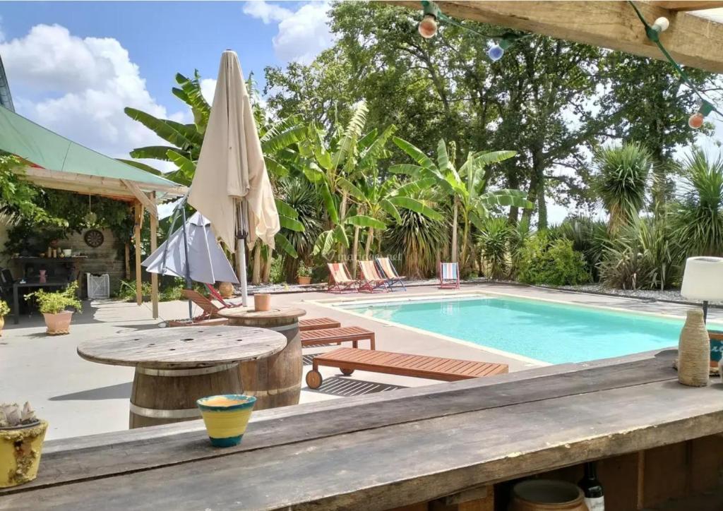 une piscine avec une table, des chaises et un parasol dans l'établissement Métairie de Galeben, à Saint-Jean-de-Marsacq