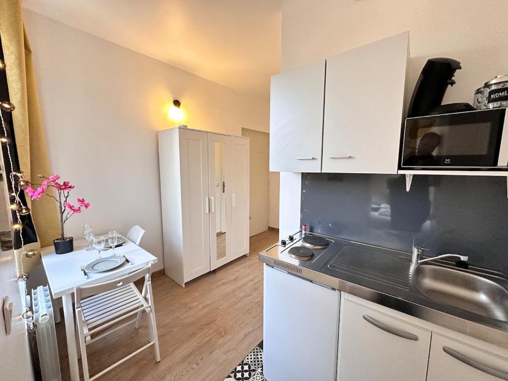 une cuisine avec des placards blancs et une petite table dans l'établissement Bali 8 studio cosy proche centre ville, à Reims