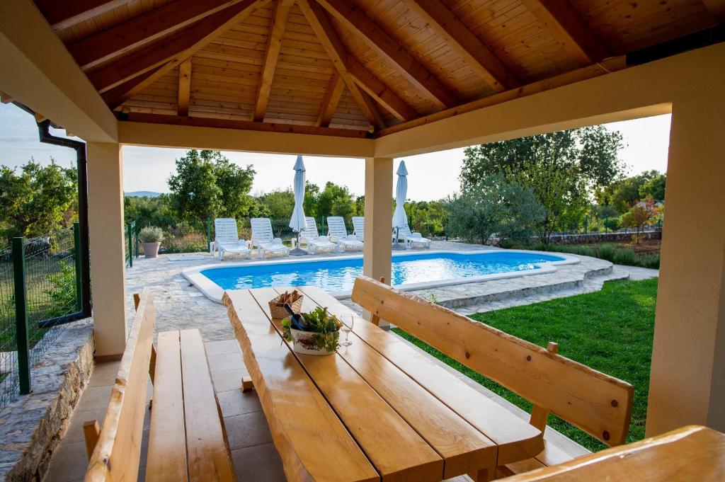 a patio with a wooden bench next to a swimming pool at Villa Magic with heated pool in Trbounje