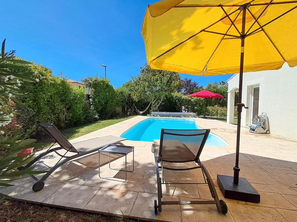 deux chaises et un parasol à côté d'une piscine dans l'établissement Villa au calme, jardin, piscine, jacuzzi, à Saussan