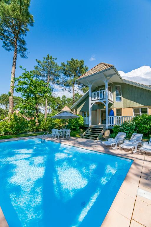 une piscine devant une maison dans l'établissement Lagrange Vacances - Eden Club, à Lacanau-Océan