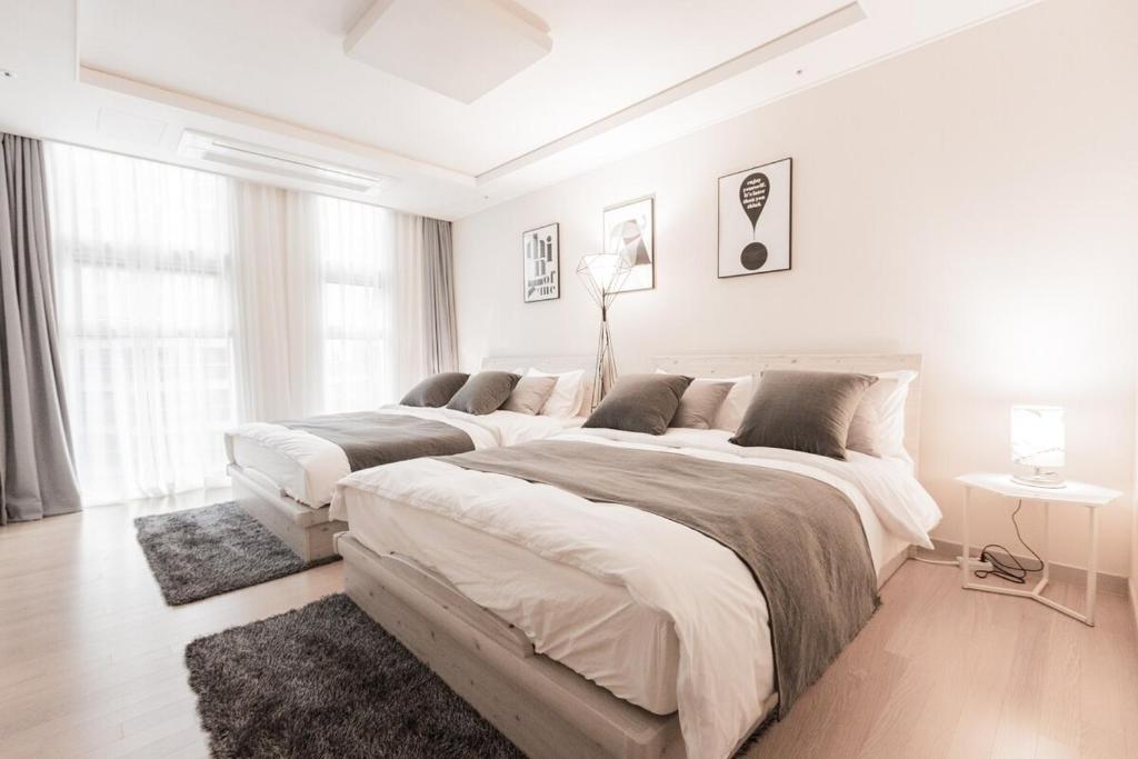 une chambre blanche avec deux grands lits dans l'établissement Seoul Station Sky Lounge House, à Séoul