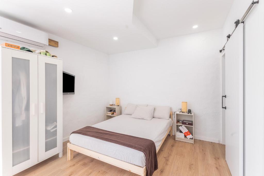 a white bedroom with a bed and a tv at Portblanc Loft in Arenys de Mar