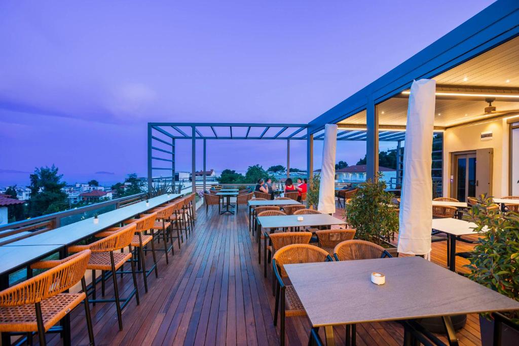 restauracja ze stołami i krzesłami na balkonie w obiekcie Hotel Vozina w mieście Metamorfosi