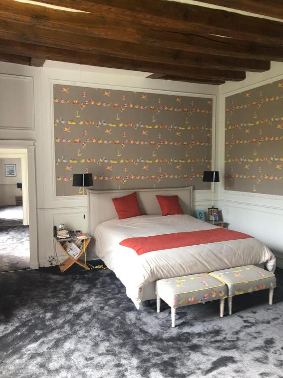 - une chambre avec un grand lit et un mur recouvert de papier peint dans l'établissement Maison de caractère, à Tours