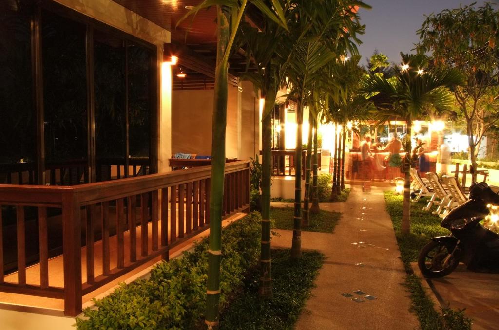 a walkway with palm trees in front of a building at Katanoi Resort in Kata Beach