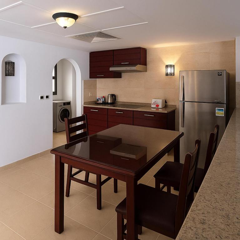a kitchen with a table and a stainless steel refrigerator at Marina Resort Port Ghalib, a member of Radisson Individuals in Port Ghalib
