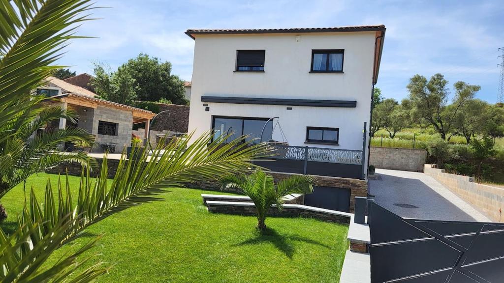 une maison blanche avec un palmier devant dans l'établissement Maison moderne avec spa Le Bosc Salagou, à Le Bosc