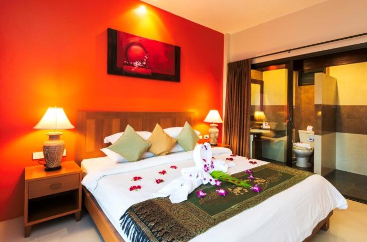 a bedroom with a large white bed with flowers on it at Katanoi Resort in Kata Beach