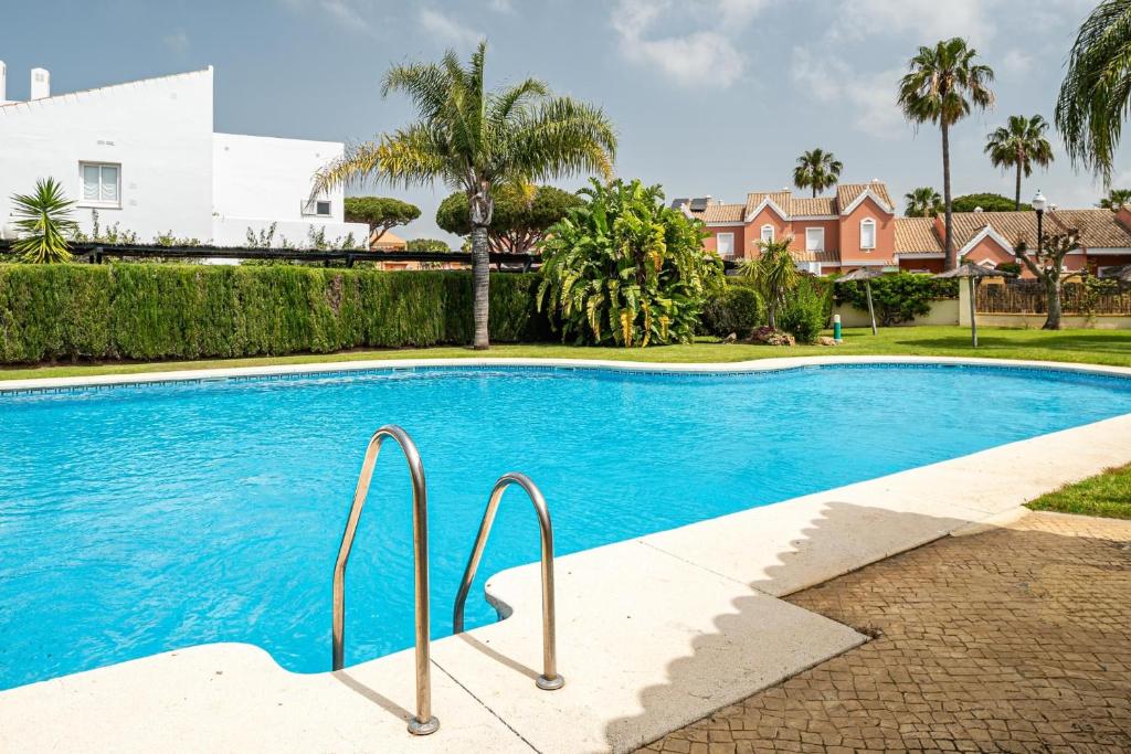 una piscina in una casa con palme di Brisamar a Chiclana de la Frontera