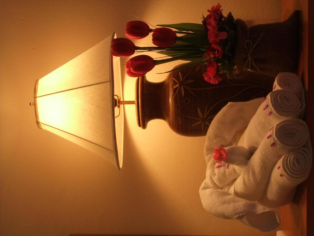 a lamp with towels and a vase of flowers on a wall at Katanoi Resort in Kata Beach