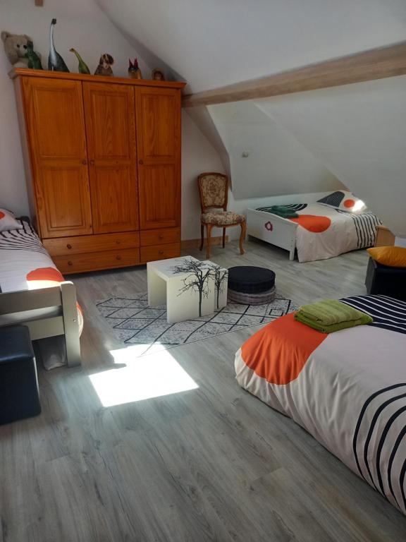 a bedroom with two beds and a cabinet and a chair at 4 Chambres et dortoir 5x90 in Cérans-Foulletourte