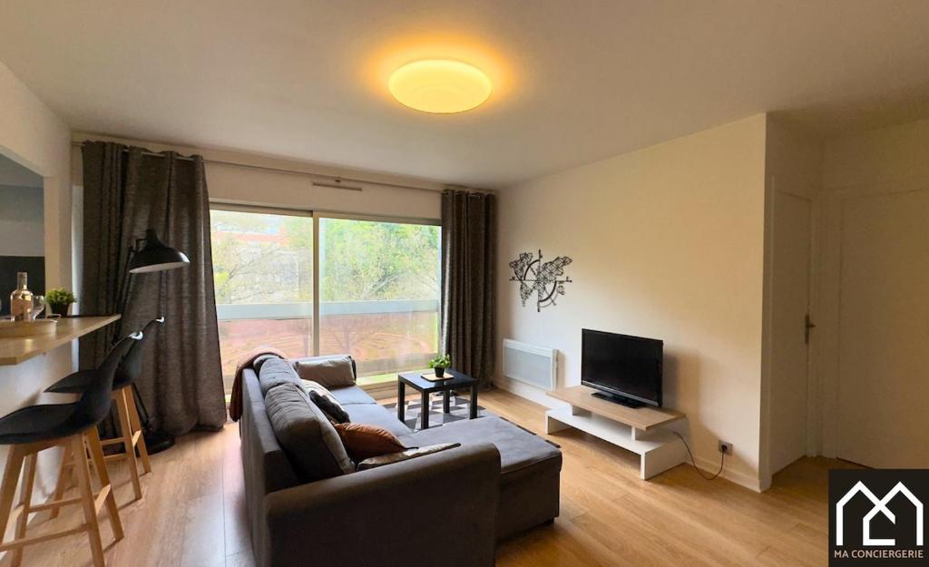 un salon avec un canapé et une télévision dans l'établissement Côté Remparts, Central, Face à la Vieille Ville & Parking Privé GRATUIT, à Boulogne-sur-Mer