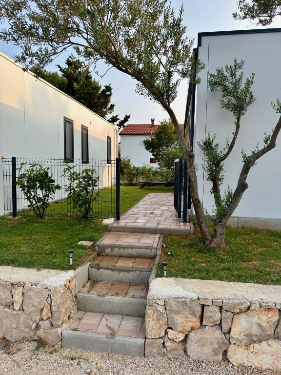 a stone walkway next to a building with a tree at Holiday Home Ahil 10 in Pakoštane