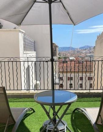 une table et des chaises sur un balcon avec un parasol dans l'établissement Hôtel Le Capitol, à Marseille
