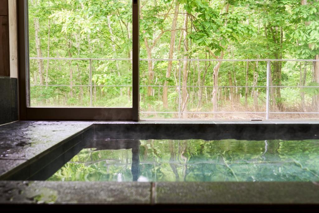 a room with a window and a pool of water at Uli Villa Onsen in Niseko