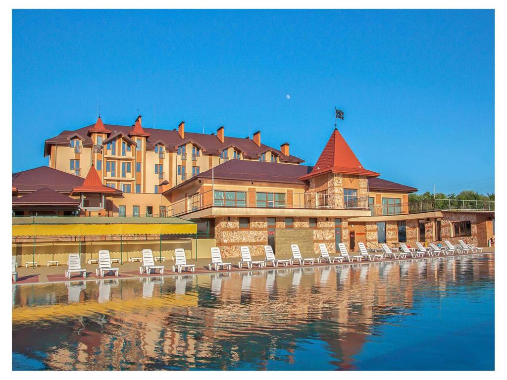 un grand bâtiment avec des chaises en face de l'eau dans l'établissement Zolota Gora Hotel-Rancho, à Oujhorod