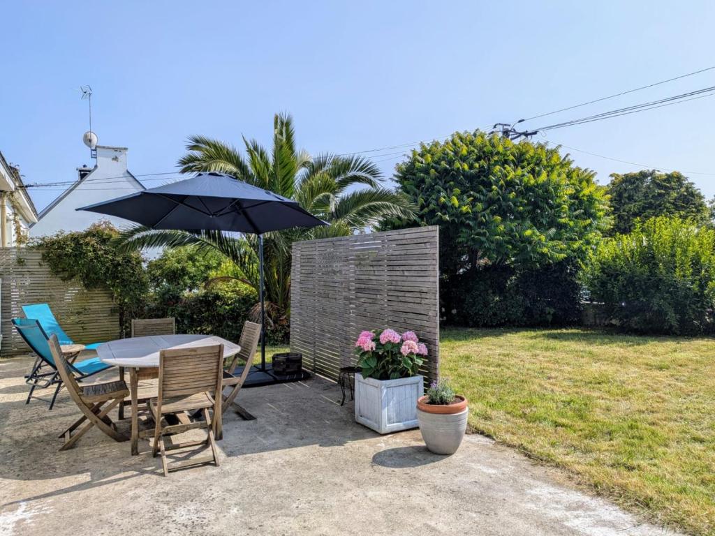 un patio avec une table, des chaises et un parasol dans l'établissement La maison de Yali, à Auray