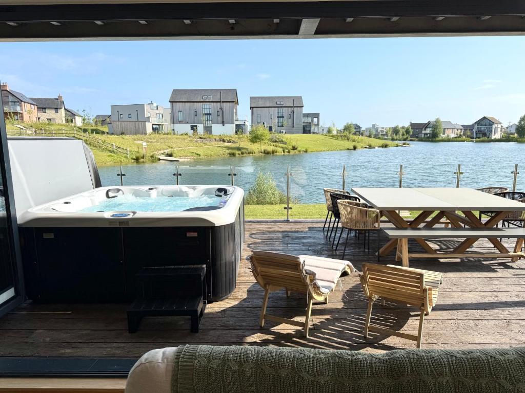 a hot tub on a deck with a table and chairs at Still Waters - Luxury Lakeside Retreat with Hot Tub in Warmwell