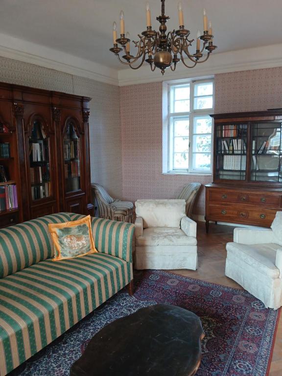 a living room with a couch and a chair and a chandelier at Chateau Probitz - apartmá na panském dvoře 