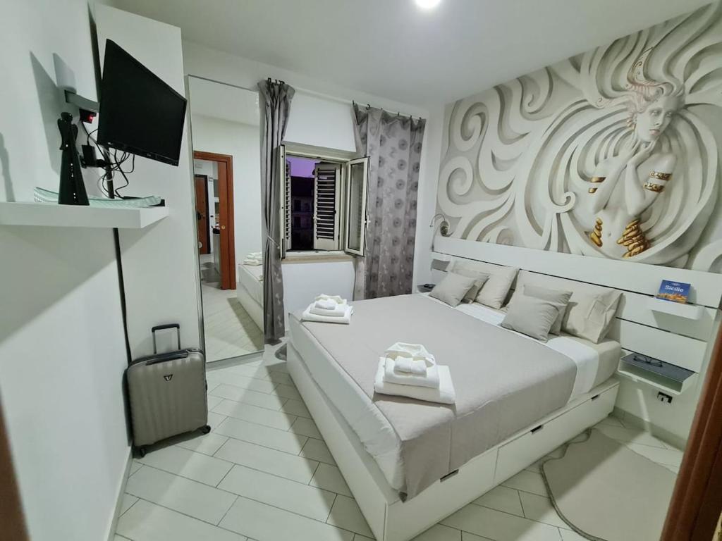 a white bedroom with a bed and a television at Apartman SOFIA - close to the railway station in Scalea